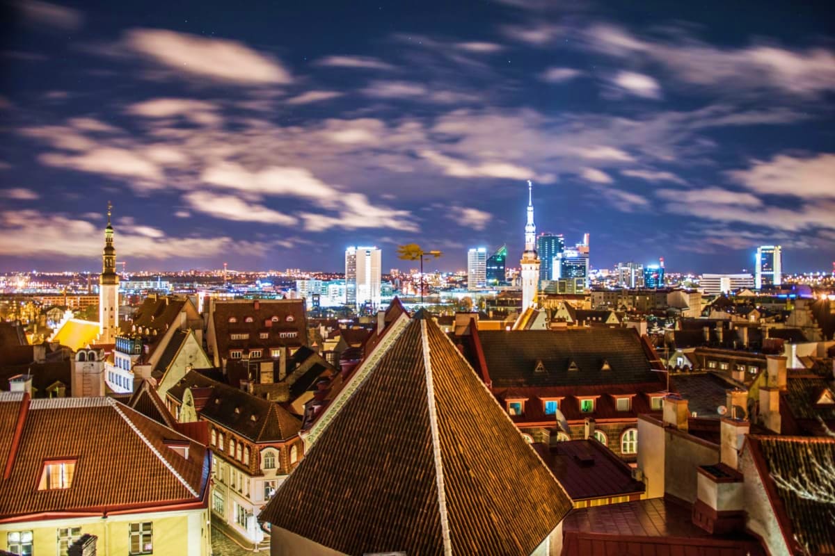 Aerial view of Tallinn's medieval old town with red-roofed buildings and modern skyline with church spires at dusk