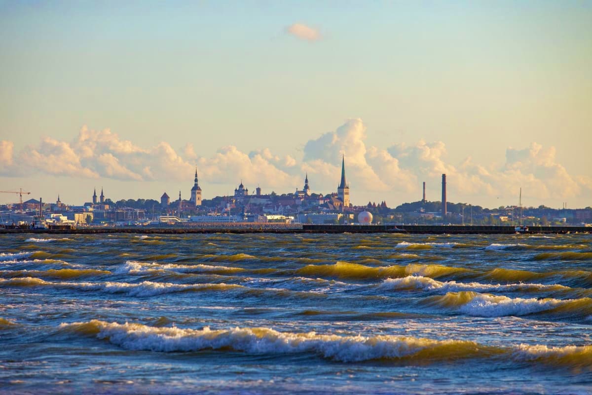 Tallinn old town skyline with church spires viewed across the Baltic Sea with rolling waves in foreground
