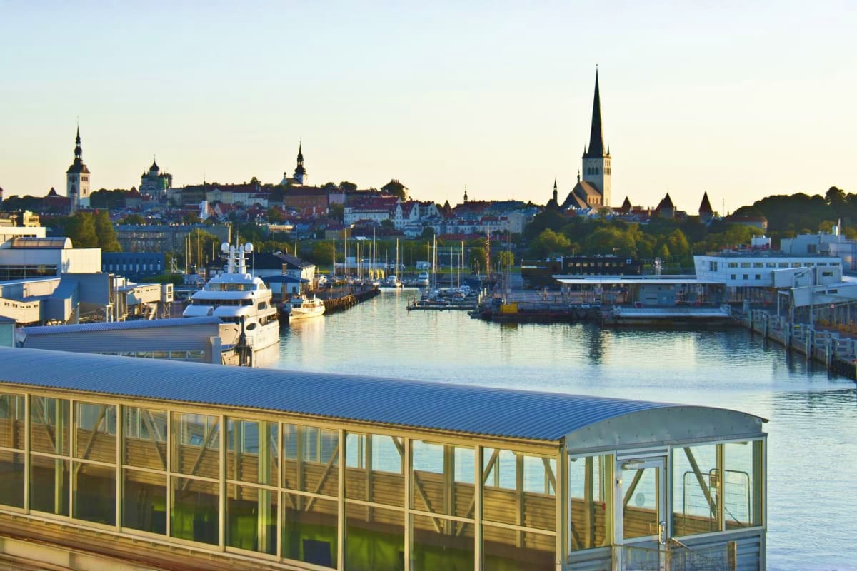 Tallinn harbor with medieval Old Town skyline, sailboats, and waterfront buildings at sunset