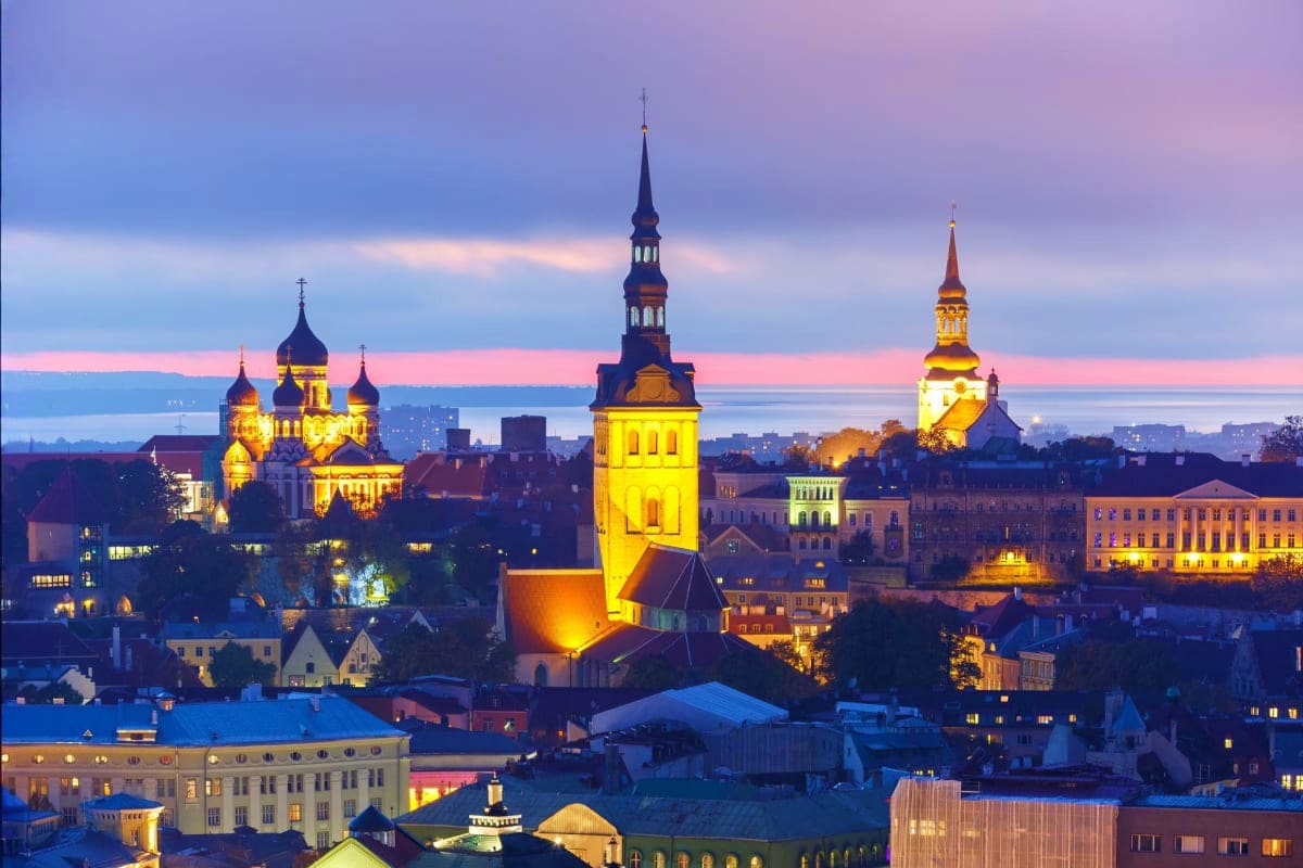 Tallinn, Estonia skyline at dusk with illuminated Orthodox cathedrals and church spires overlooking the old town and harbor