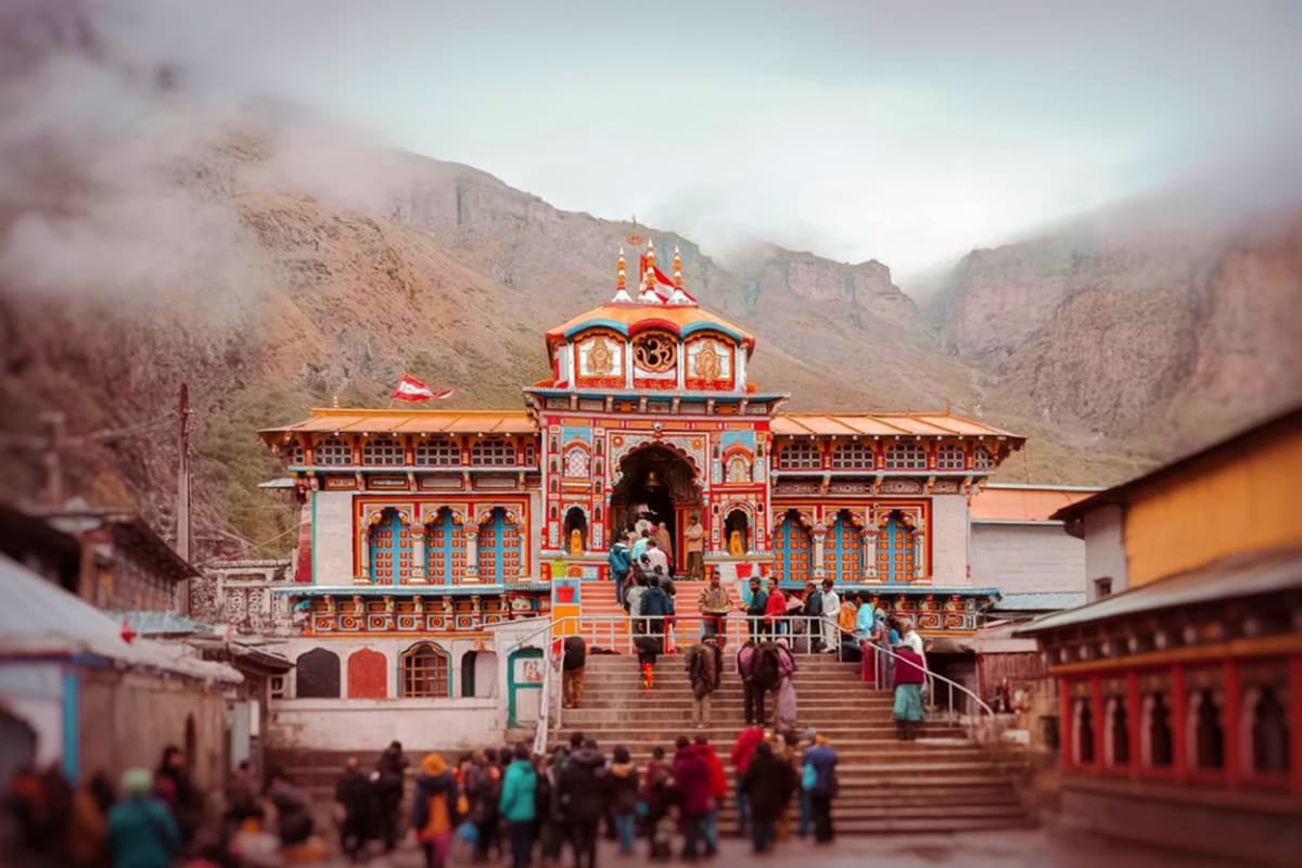 Kedarnath Temple with red and gold architecture nestled in misty Himalayan mountains, pilgrims ascending stone steps to entra