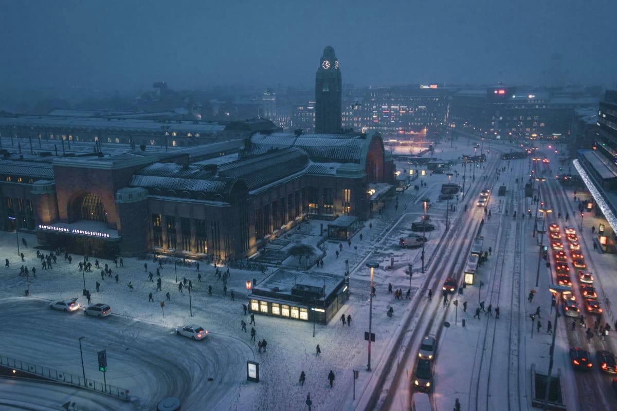 Snowy winter evening at Helsinki Central Station and Kaivokatu square with illuminated historic architecture and city lights