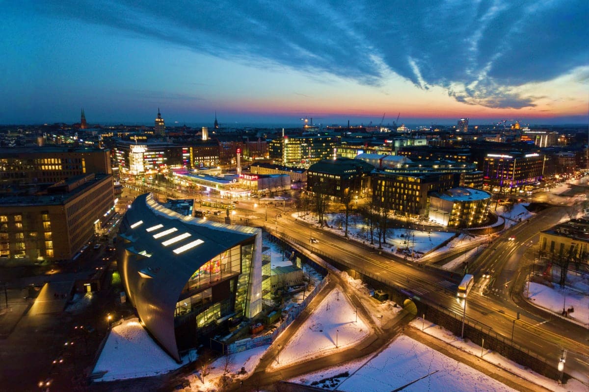 Aerial view of Helsinki city skyline at twilight with illuminated buildings, snow-covered streets, and modern architecture at