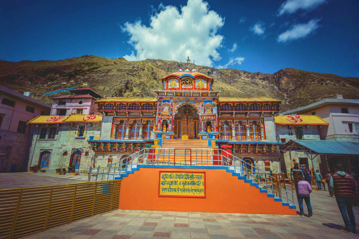 Colorful Hindu temple with ornate orange and blue facade nestled in barren mountains under clear blue sky
