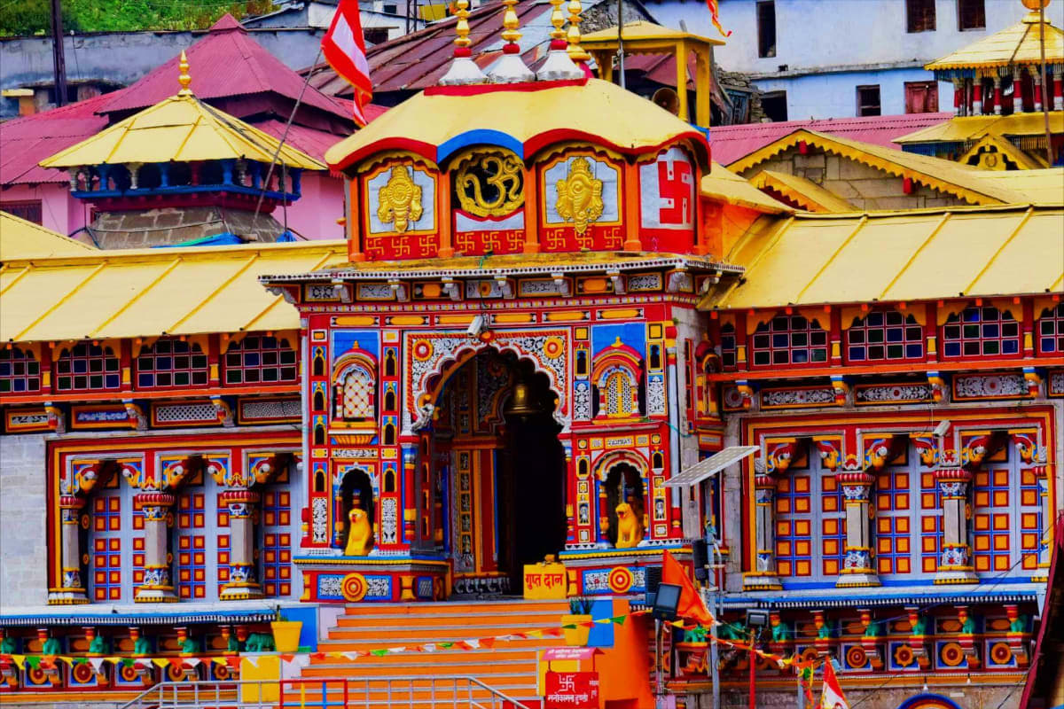 Colorful Hindu temple facade with red and gold ornate doors, yellow-roofed pavilions, and golden deity statues in Haridwar, I