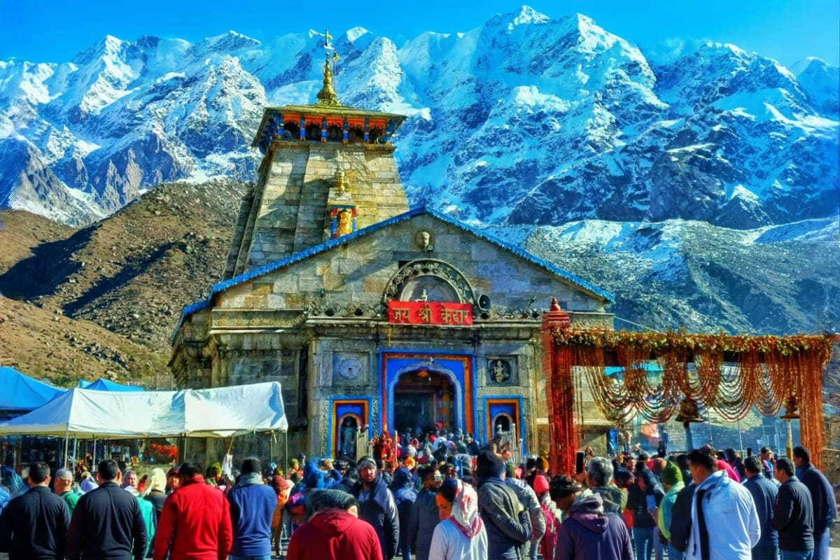 Kedarnath Temple with snow-capped Himalayan peaks in background and pilgrims gathered during Char Dham Yatra pilgrimage