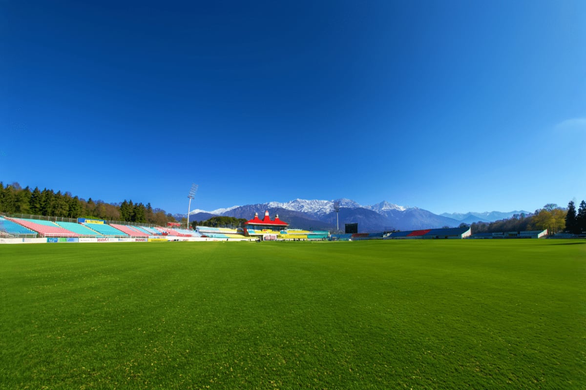 Alpine football stadium with snow-capped Himalayan mountains in background under clear blue sky