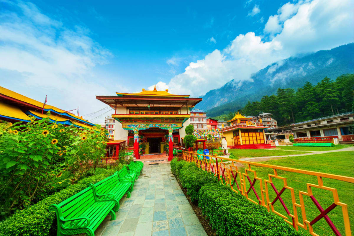 Snow Valleys And Hot Springs Tour In Manali And Manikaran Colorful Buddhist monastery with golden roofs and red decorative elements nestled in green valley with mountain backdrop and