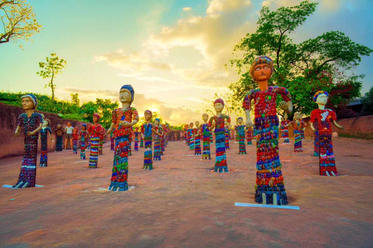 Colorful traditional wooden figures displayed in a row at sunset in Himachal Pradesh, India cultural landmark.
