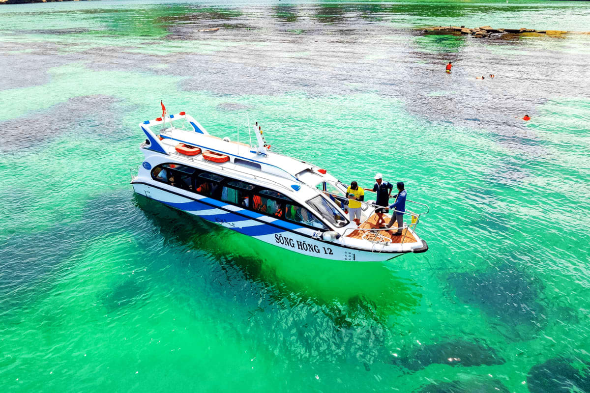 Tourist speedboat with passengers in turquoise shallow waters off Vietnamese coast, snorkeling and island excursion activity