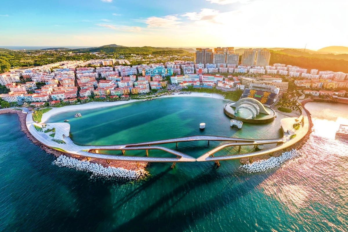 Aerial view of modern curved architectural landmark with crescent beach and turquoise water in coastal Vietnamese resort town