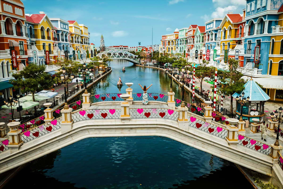 Colorful colonial buildings lining a canal with a white bridge decorated with red and pink hearts in Phu Quoc