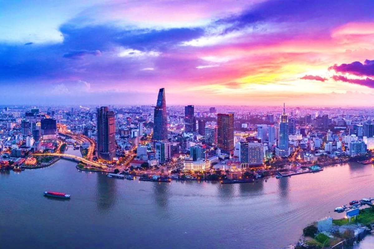 Ho Chi Minh City skyline at sunset with illuminated skyscrapers, Saigon River, and colorful purple-pink sky with clouds