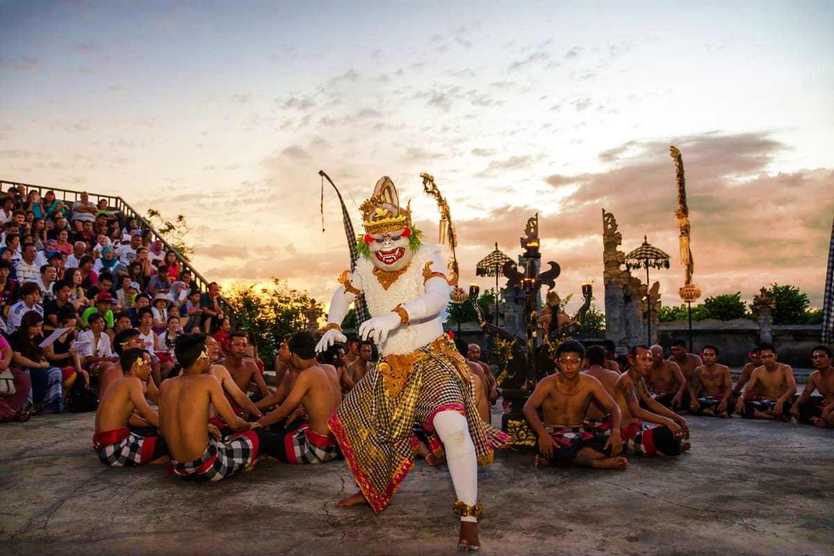 Traditional Balinese Kecak fire dance performance with demon character and shirtless dancers at outdoor temple venue during s