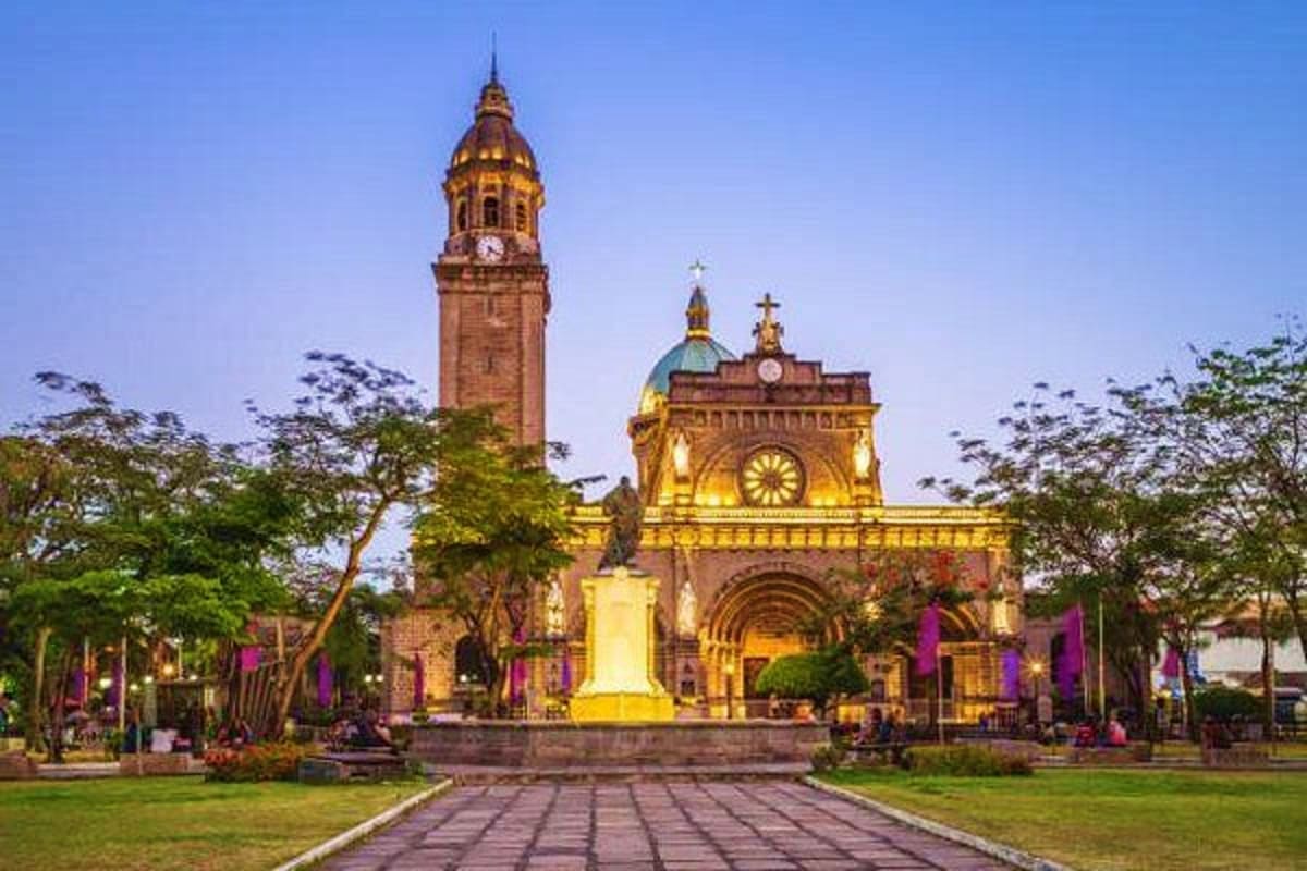 Ultimate Manila and Cebu Holiday Package Illuminated historic church and bell tower at dusk in Manila, Philippines with manicured gardens and stone pathway