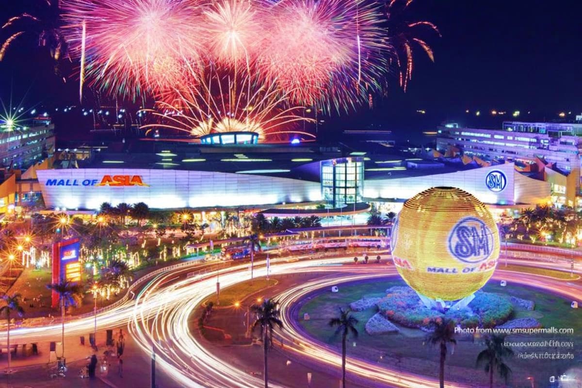 Ultimate Manila and Cebu Holiday Package Night fireworks display over illuminated Mall of Asia in Manila with light trails from traffic and golden egg monument visibl