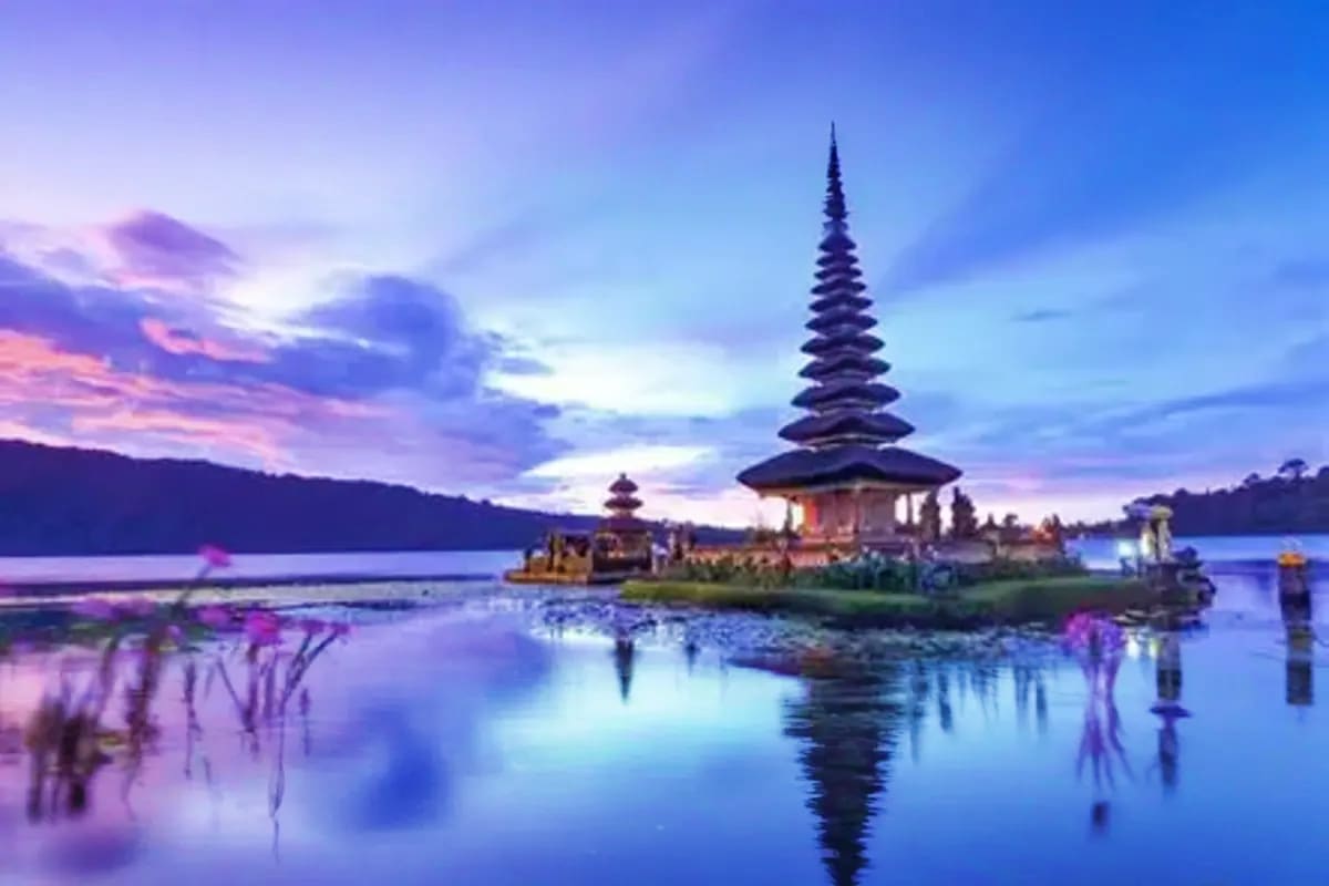 Pura Ulun Danu temple on lake island at twilight with purple sky reflection in still water, Bali Indonesia