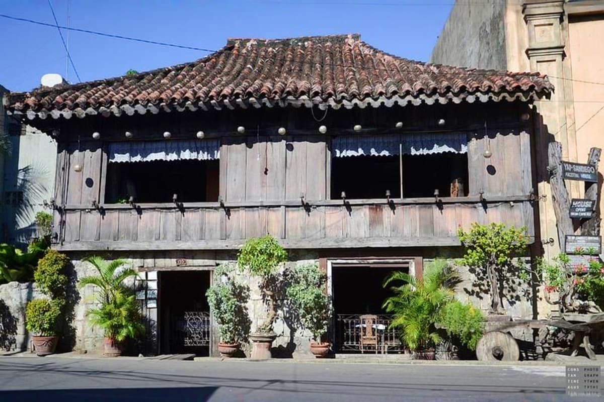 6 Days Manila and Cebu Holiday Package Historic Spanish colonial building with curved tile roof, wooden shutters, and potted plants in Manila's Intramuros district