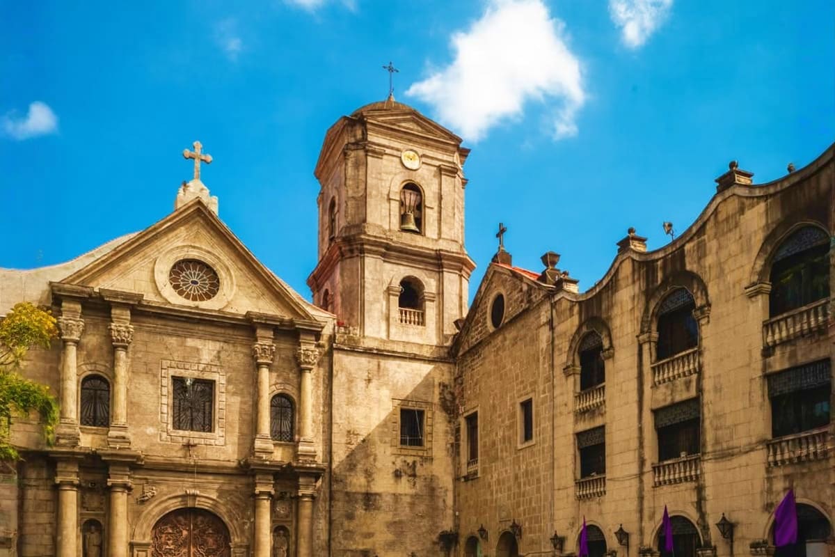 Best of Manila and Boracay Tour Package Historic stone cathedral with bell tower and cross under blue sky in Manila, Philippines