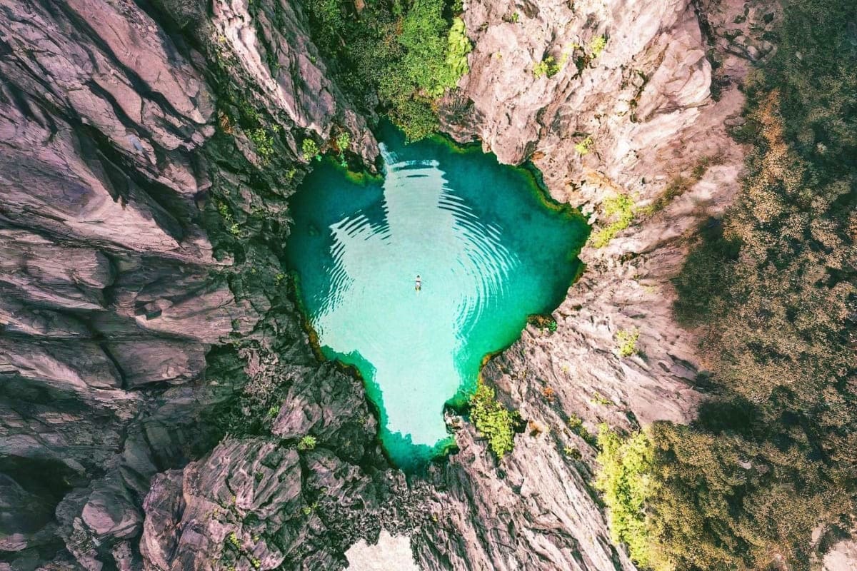Philippines Island Escape with Manila El Nido and Cebu Aerial view of turquoise lagoon surrounded by dramatic gray limestone cliffs with green vegetation in El Nido, Philippines
