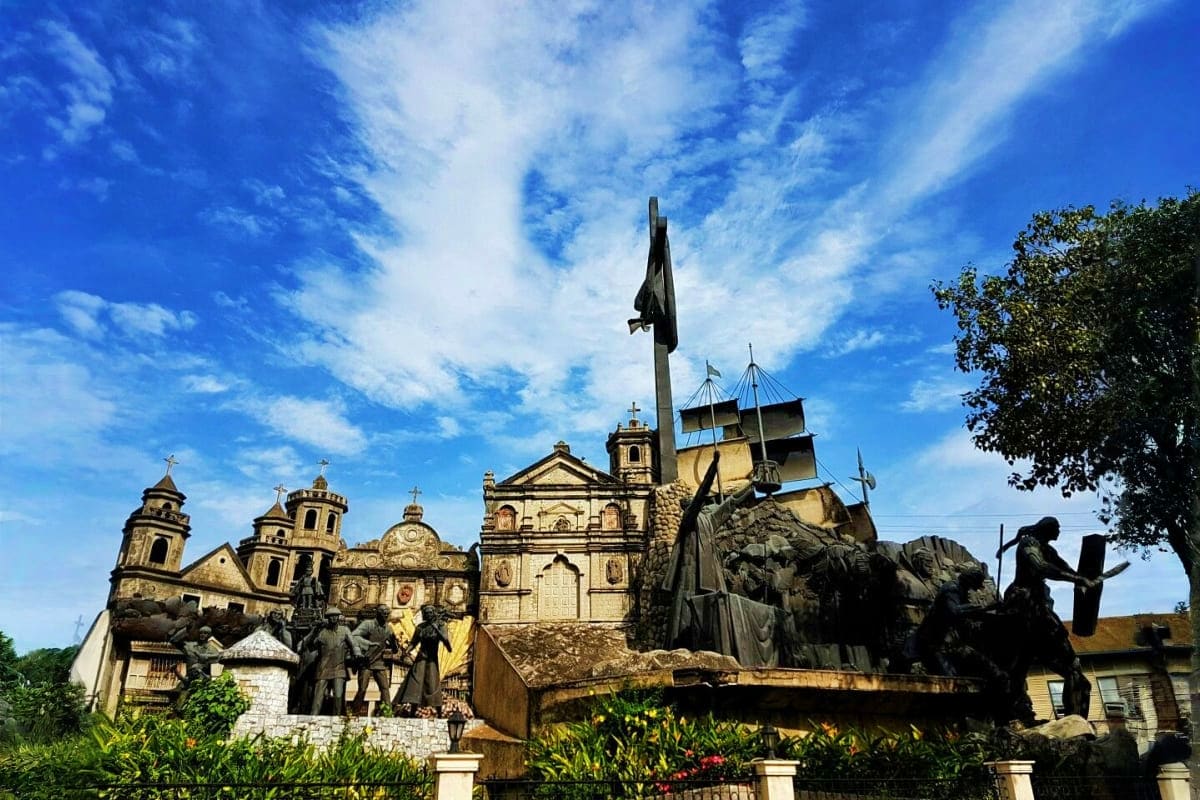 Philippines Island Escape with Manila El Nido and Cebu Historic Catholic cathedral with bronze statues and monuments in tropical plaza setting under blue sky