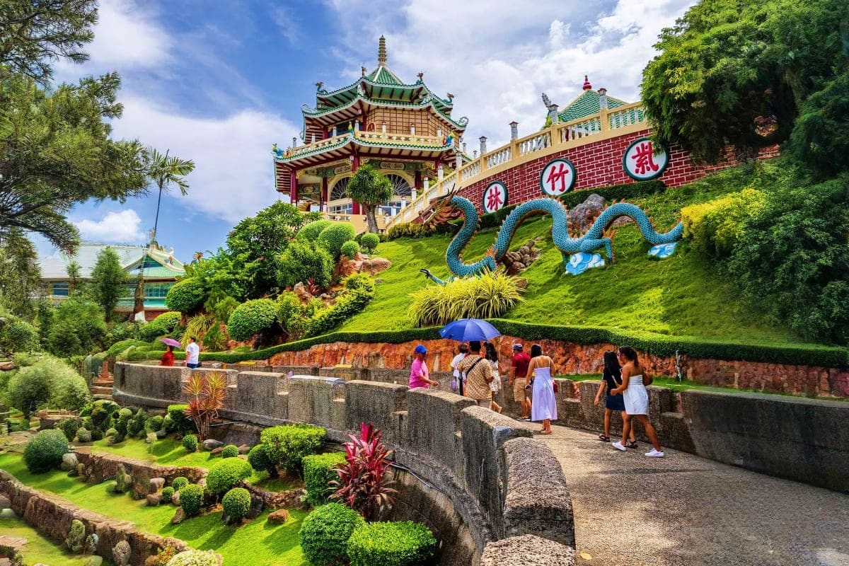 Philippines Island Escape with Manila El Nido and Cebu Chinese temple pagoda with green dragon sculpture on hillside, tourists walking on stone pathway in lush tropical gardens
