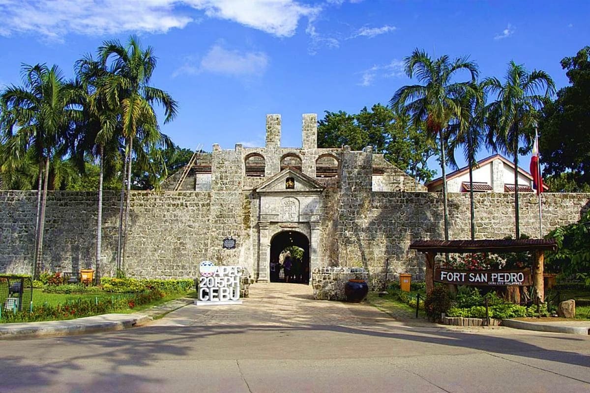 Tropical Philippines Vacation Fort San Pedro stone fortress entrance in Cebu, Philippines with palm trees and clear blue sky