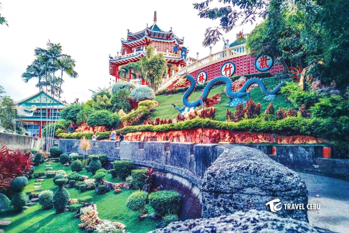 Tropical Philippines Vacation Chinese temple with red and gold pagoda roof, blue dragon sculpture, and manicured gardens in tropical Philippines setting