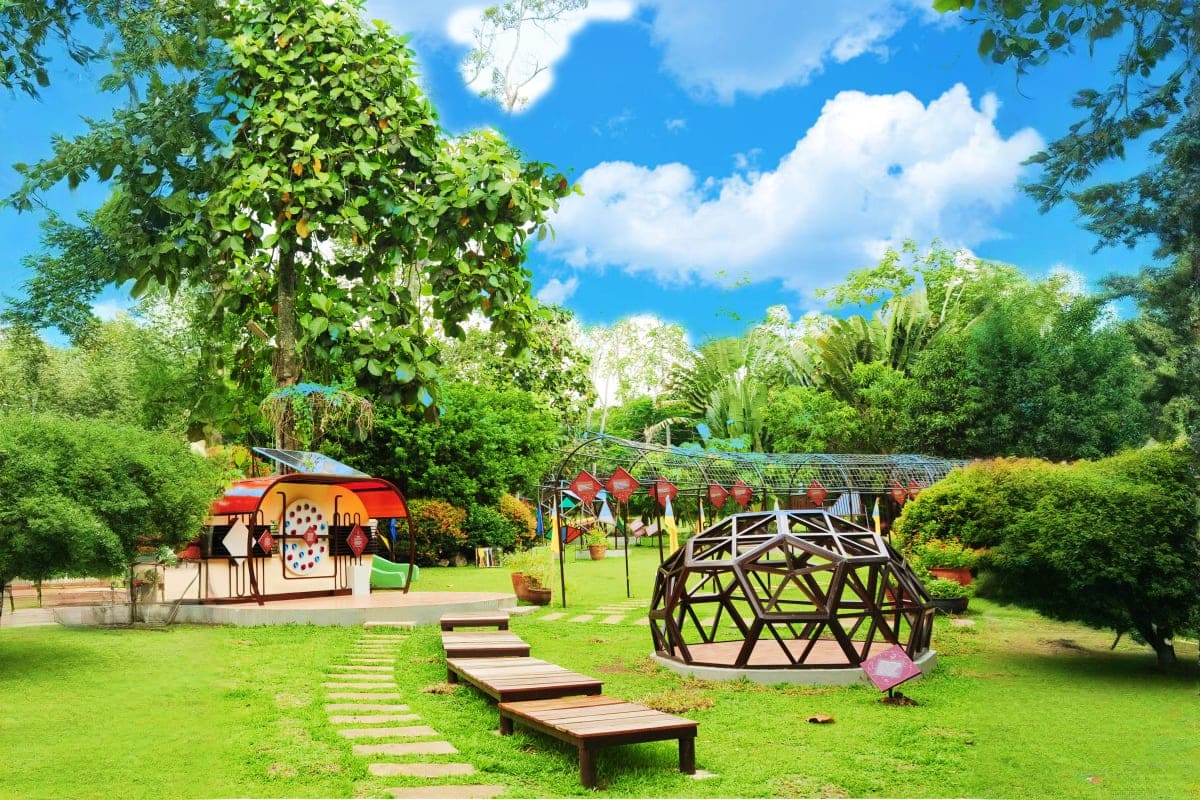 Davao to Siargao Adventure Tour Botanical garden with interactive art installations, geometric sculpture, and lush tropical vegetation under blue sky