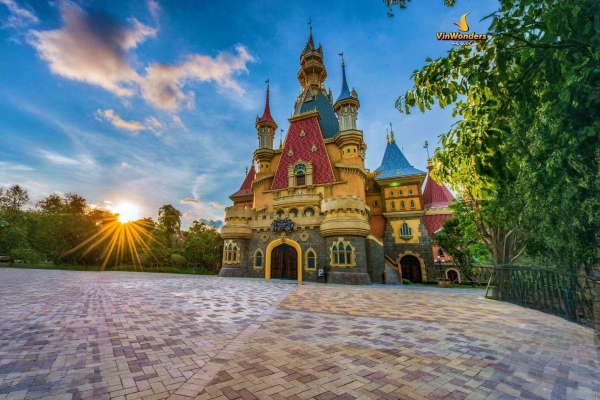 Fairytale castle at sunset with golden spires and colorful red-tiled roofs at VinWonders theme park in Phu Quoc, Vietnam
