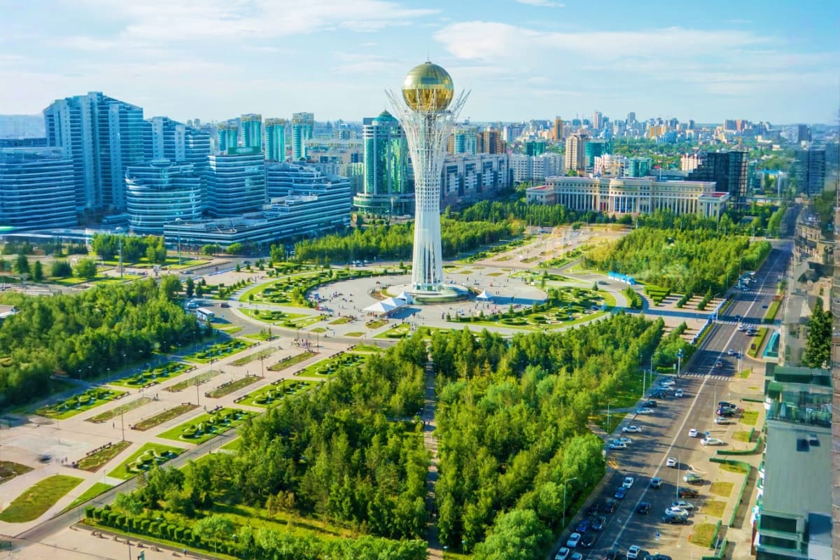 Aerial view of Bayterek Tower in Astana, Kazakhstan with surrounding parks, green trees, and modern city skyline