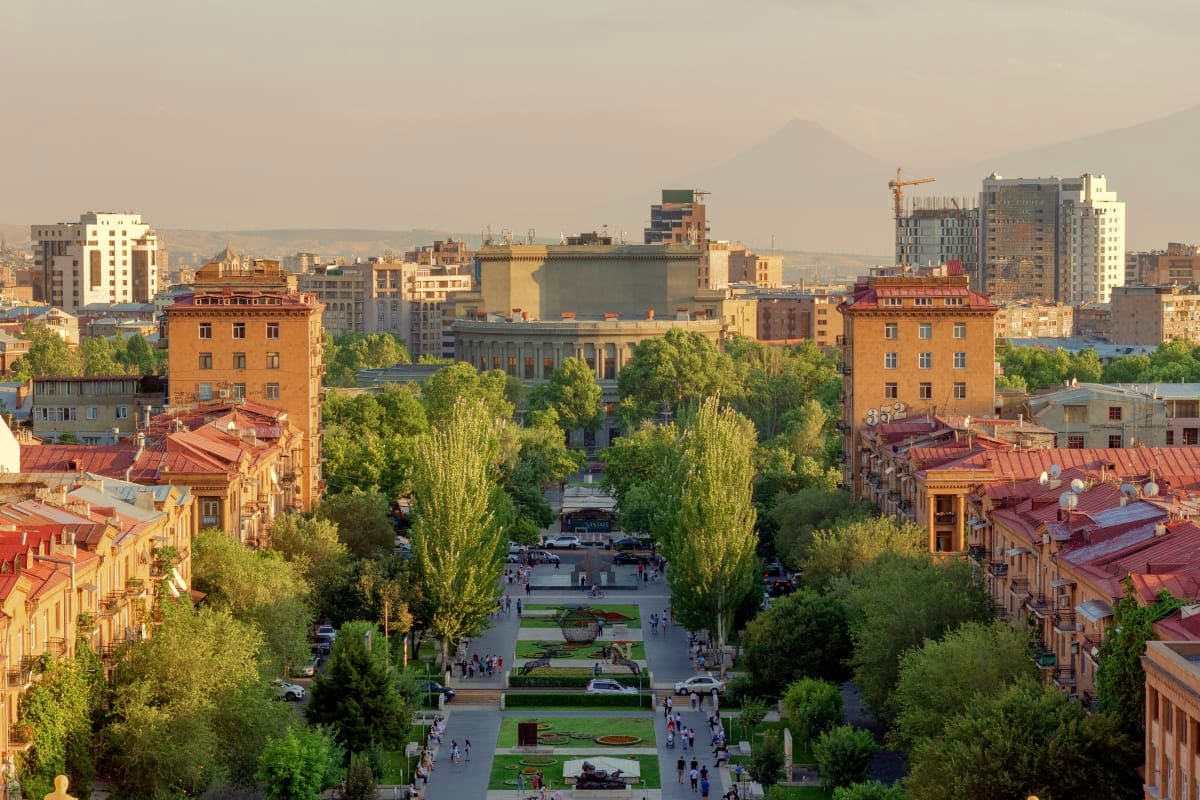 Aerial view of Yerevan city center with Republic Square, orange historic buildings, tree-lined avenue, and Mount Ararat in th