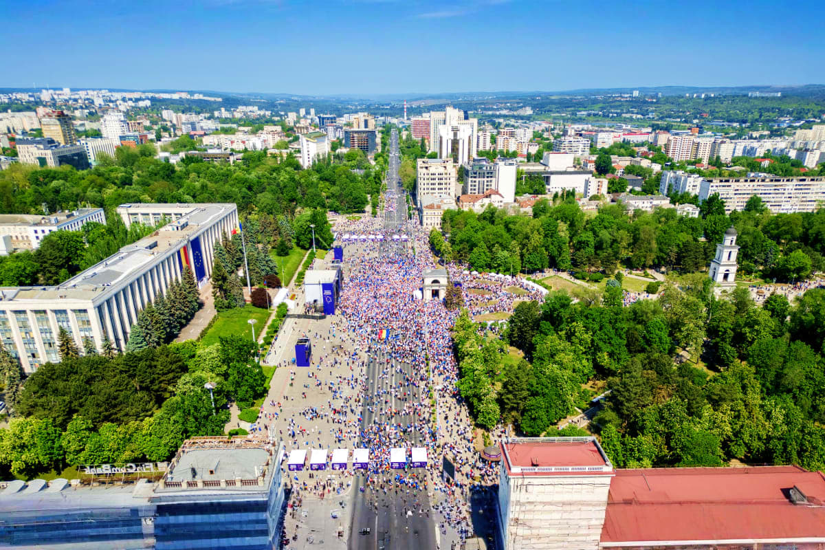 Aerial view of crowded city square and street procession in Yerevan, Armenia with surrounding apartment buildings and green t
