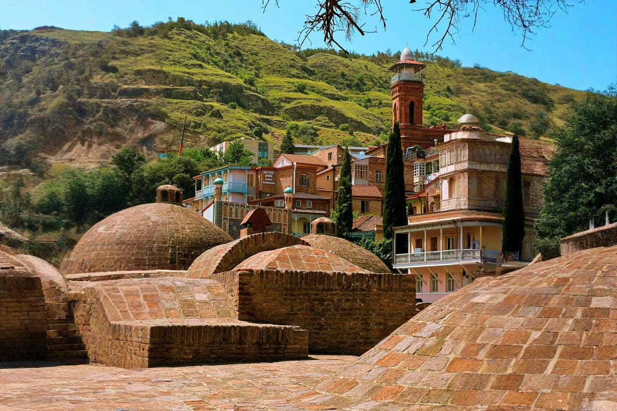 Historic stone bathhouses with domed roofs at Abanotubani thermal springs in Tbilisi, Georgia, with residential buildings and