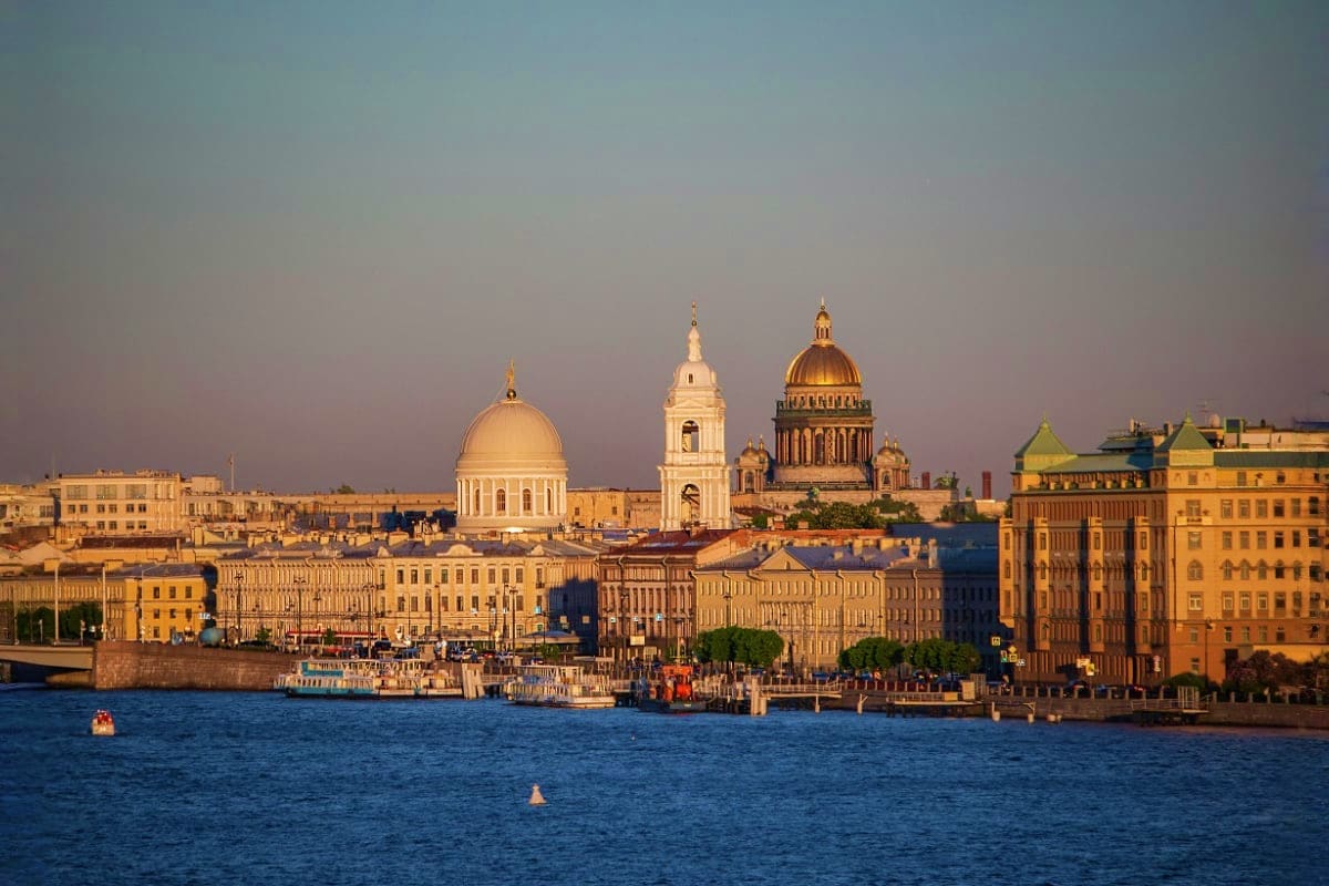 Saint Isaac's Cathedral and historic buildings along the Neva River waterfront in Saint Petersburg at sunset