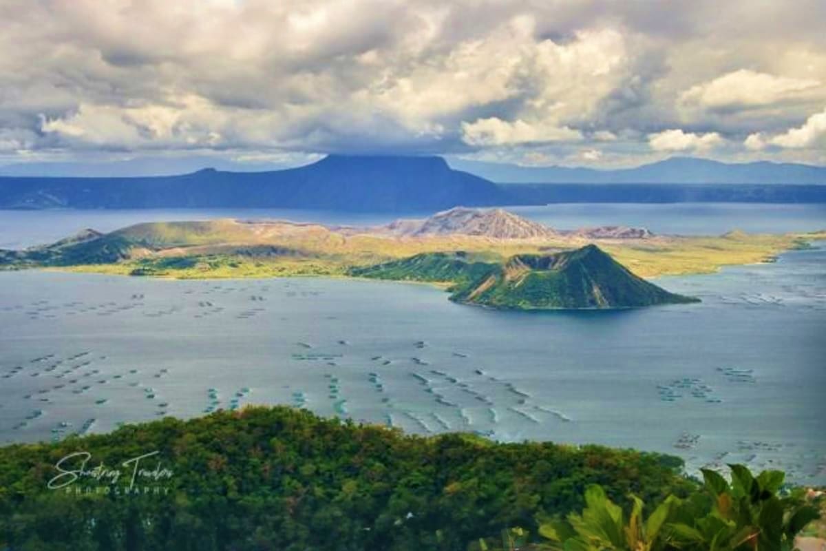 Manila Batangas Short Tour Aerial view of Taal Volcano and Taal Lake in Batangas, Philippines, with small volcanic island in foreground and mountains un