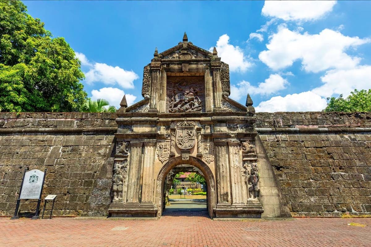 Exclusively Manila Historic stone fort gate with ornate archway and decorative crest in Manila, Philippines