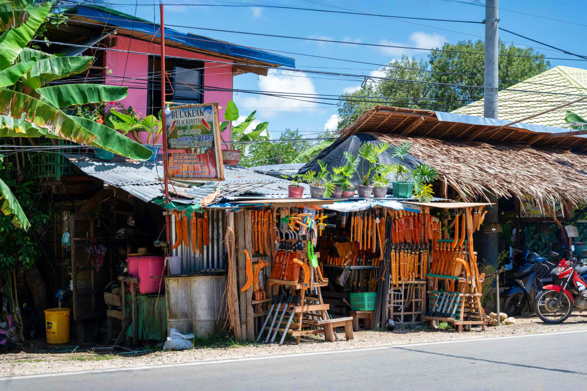 Simply Bohol Rustic wooden furniture shop in rural Bohol village with stacked chairs and hand-crafted pieces displayed under metal roof st