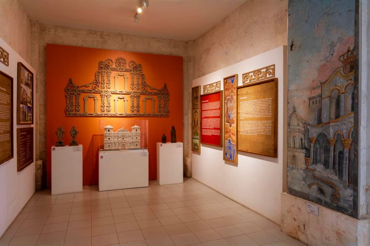 Simply Bohol Museum exhibition room displaying Bohol cultural artifacts including ornate wooden architectural panels, religious sculptures
