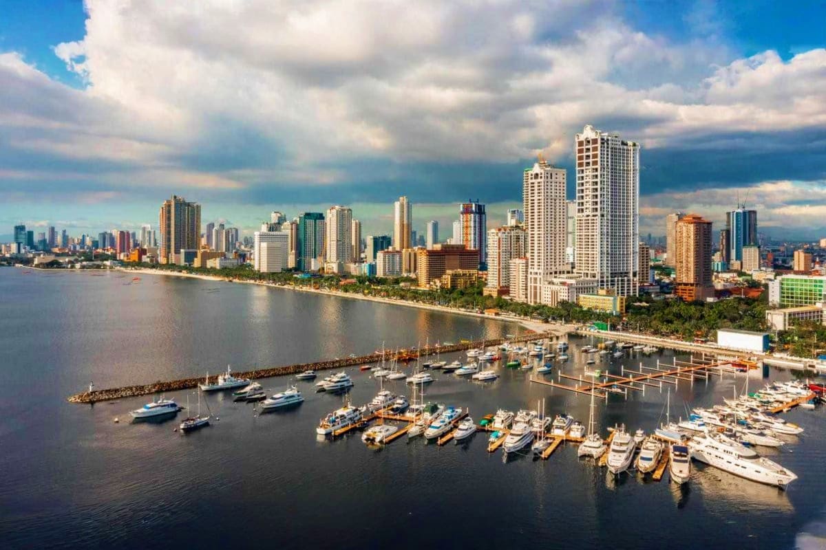 Pristine Palawan Tour Honolulu beachfront skyline with high-rise hotels and boats moored in marina under cloudy sky