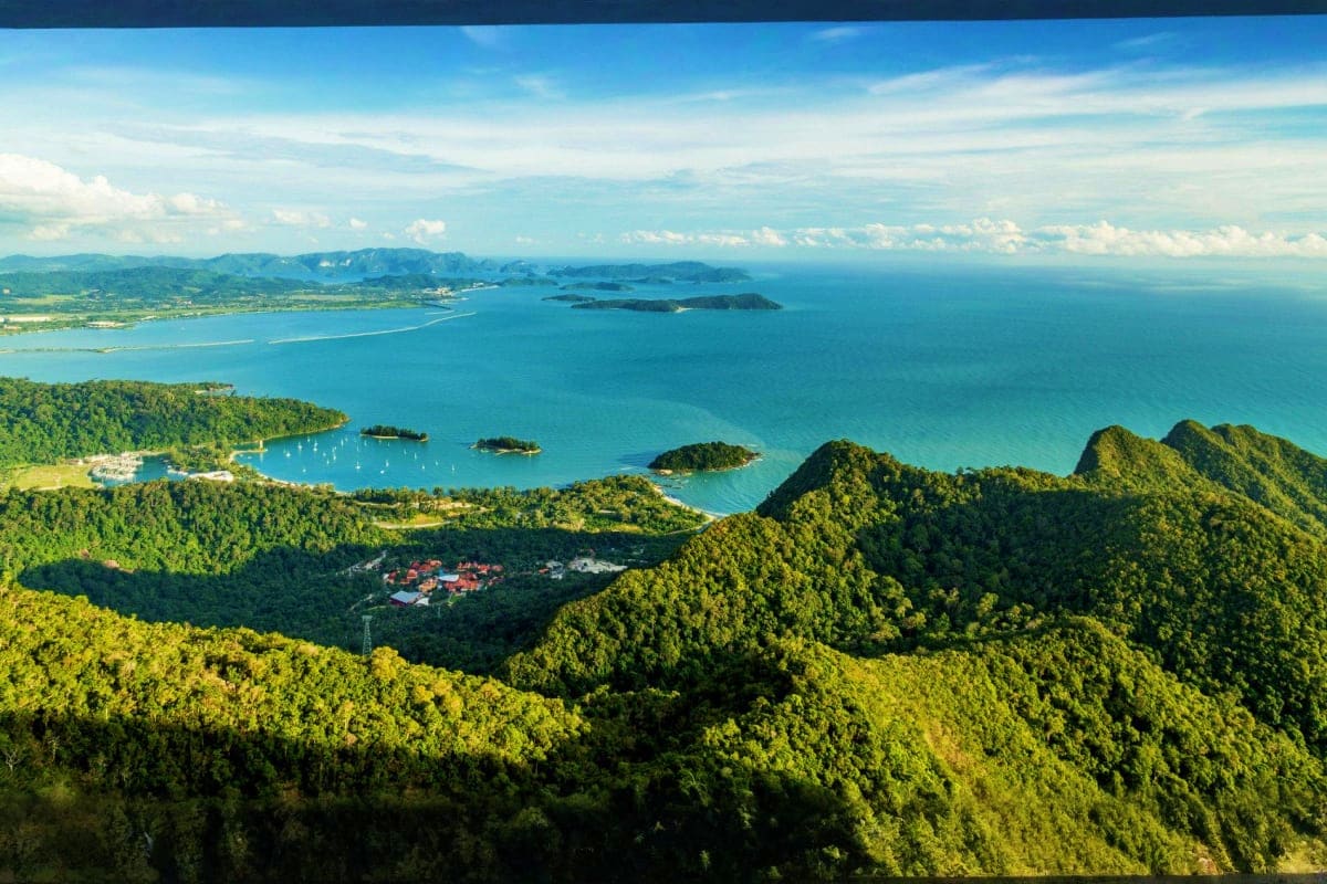 Aerial view of tropical coastal landscape with turquoise sea, forested mountains, and scattered islands in Malaysia