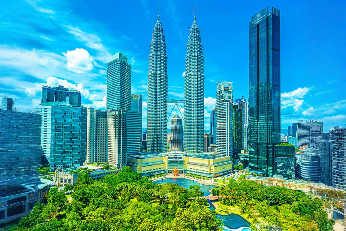 Kuala Lumpur skyline featuring Petronas Twin Towers and surrounding modern skyscrapers with green parks and blue pools below
