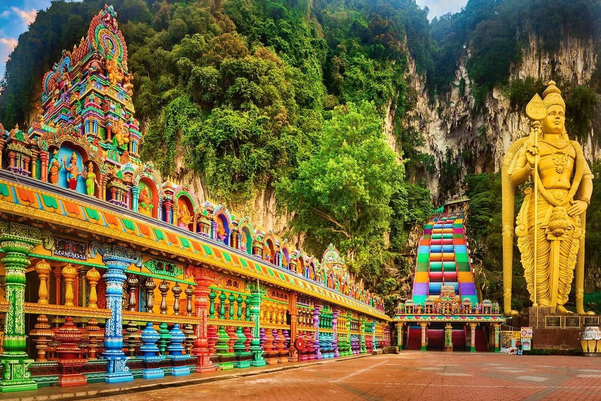 Batu Caves temple in Malaysia with colorful Hindu shrine, golden deity statue, and vibrant painted architecture nestled among