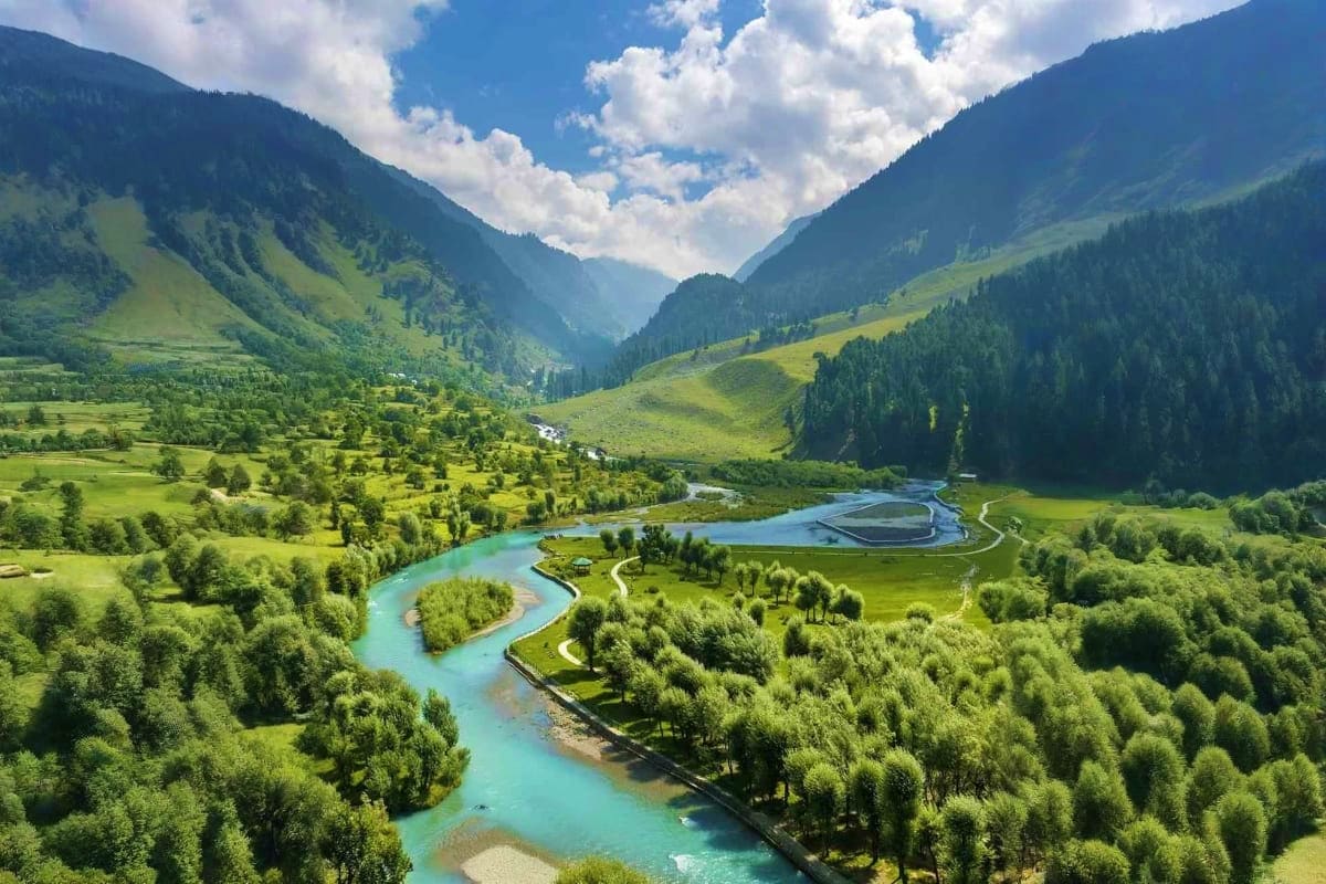 Aerial view of a turquoise river winding through a lush green valley with forested mountains and a modern building in Kashmir