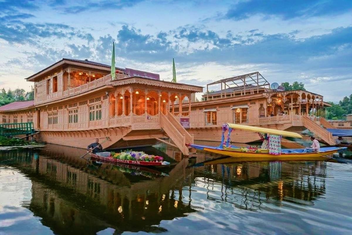 Traditional Kashmiri houseboats and wooden buildings reflected in calm backwater waters with tourists in small boats