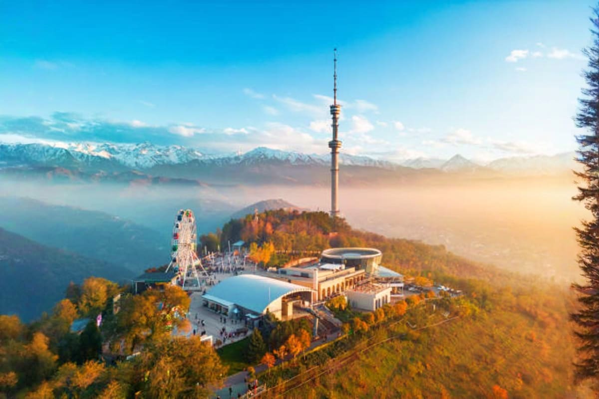 Aerial view of Assy Plateau mountain complex with Ferris wheel, observation tower, and buildings surrounded by autumn forest 