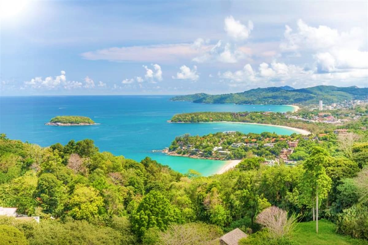 Aerial view of tropical coastal landscape in Thailand with turquoise waters, white sand beaches, green forested hills, and sm