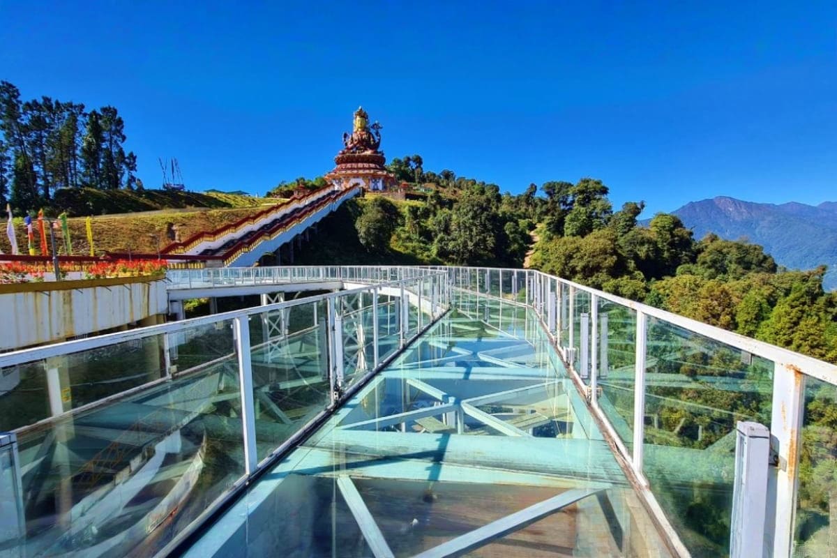 Glass skywalk at Kanyam viewpoint overlooking forested mountains and golden Buddhist temple in Namchi, Sikkim
