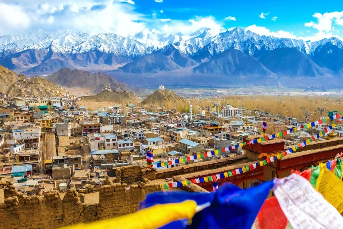 Leh cityscape with snow-capped Himalayan mountains, prayer flags, and traditional buildings in Ladakh, India