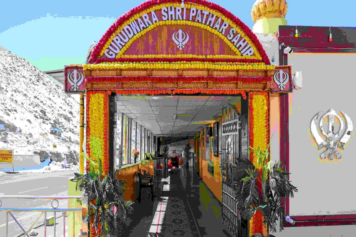 Ornately decorated entrance to Gurudwara Shri Pathar Sahib temple in Ladakh with colorful flower garlands and Sikh symbols